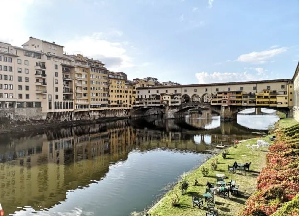 View of the Ponte Vecchio bridge over the Arno River with buildings along its banks.