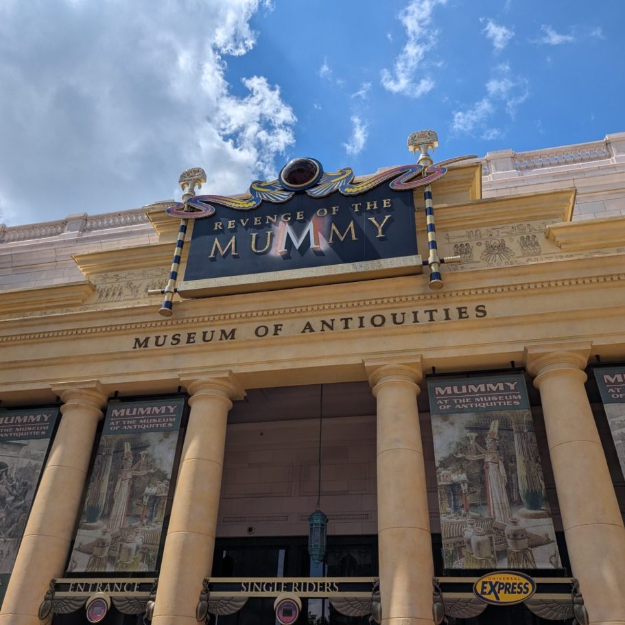 Sign for the "Museum of Antiquities" featuring a mummy theme and classical architecture.