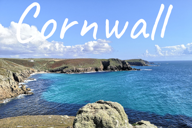 Scenic view of Cornwall coastline with blue waters and rocky cliffs.
