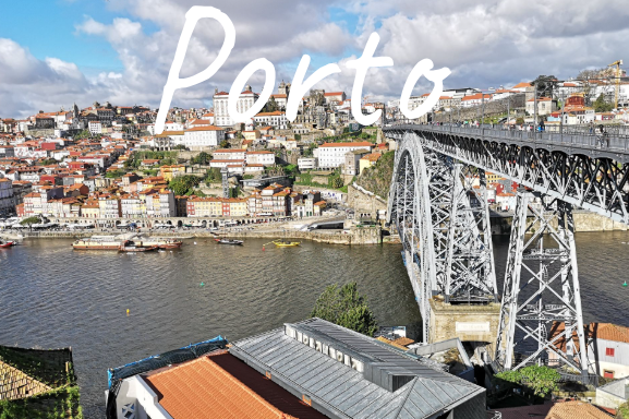 Cityscape of Porto with Luis I Bridge spanning the river and red-roofed buildings on the hillside.