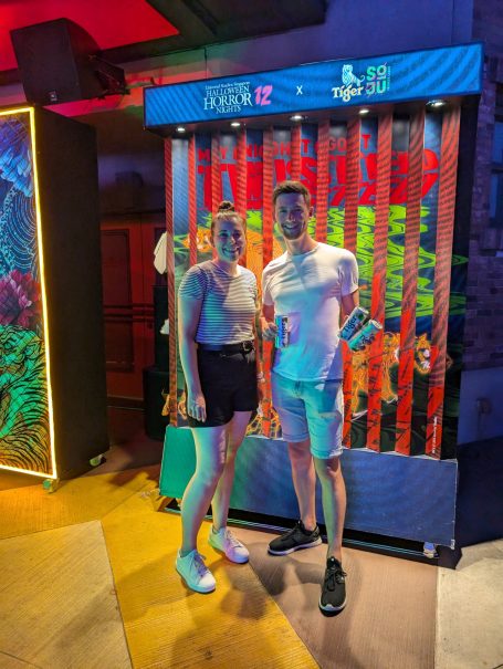 I&B's Founder & Husband standing together in front of a brightly lit colourful backdrop.