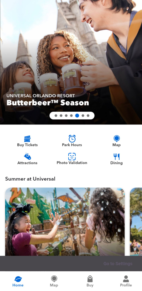 Two friends enjoying Butterbeer at a theme park with castle backdrop.
