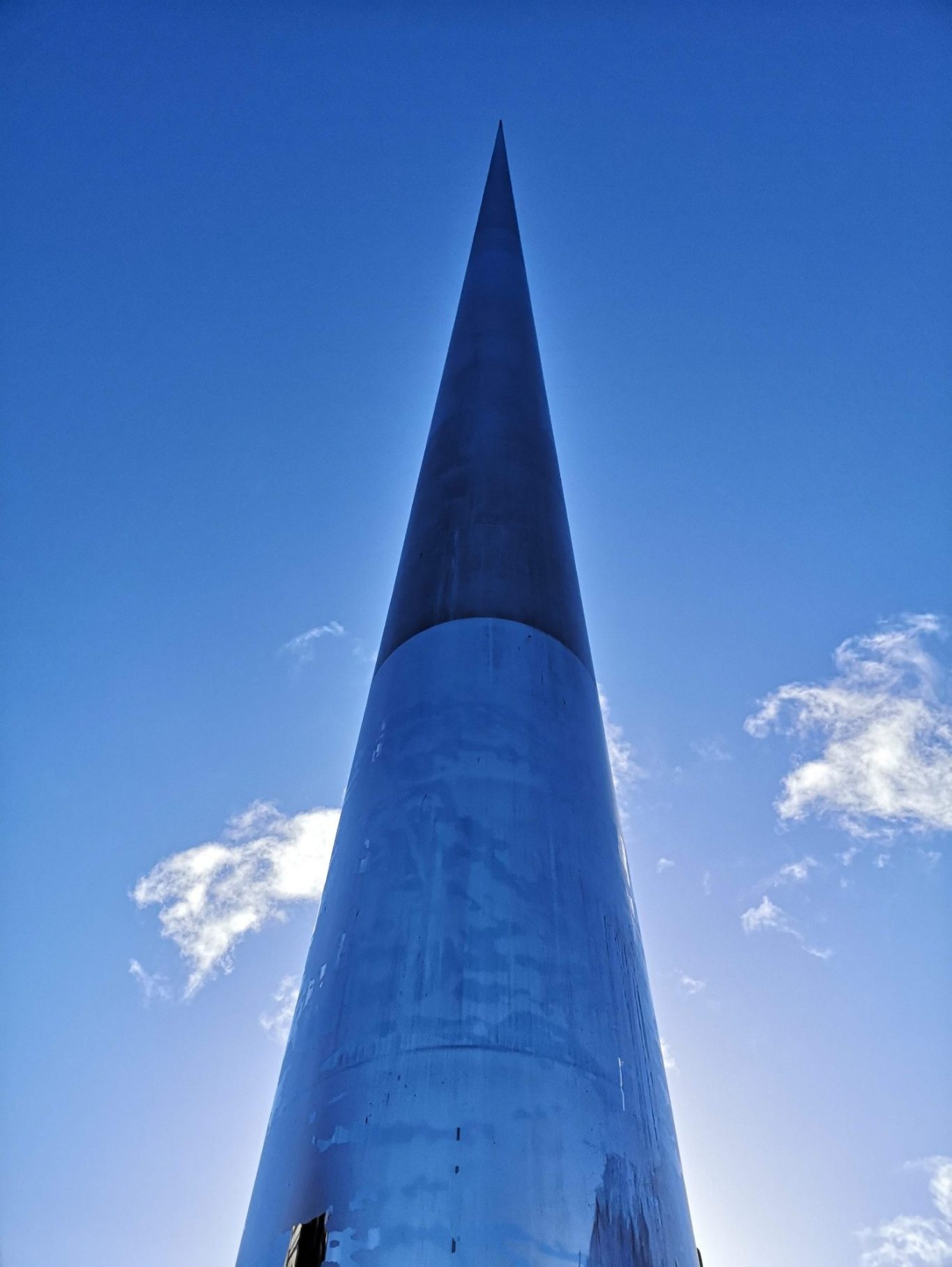 A tall, pointed structure against a clear blue sky with a few clouds.