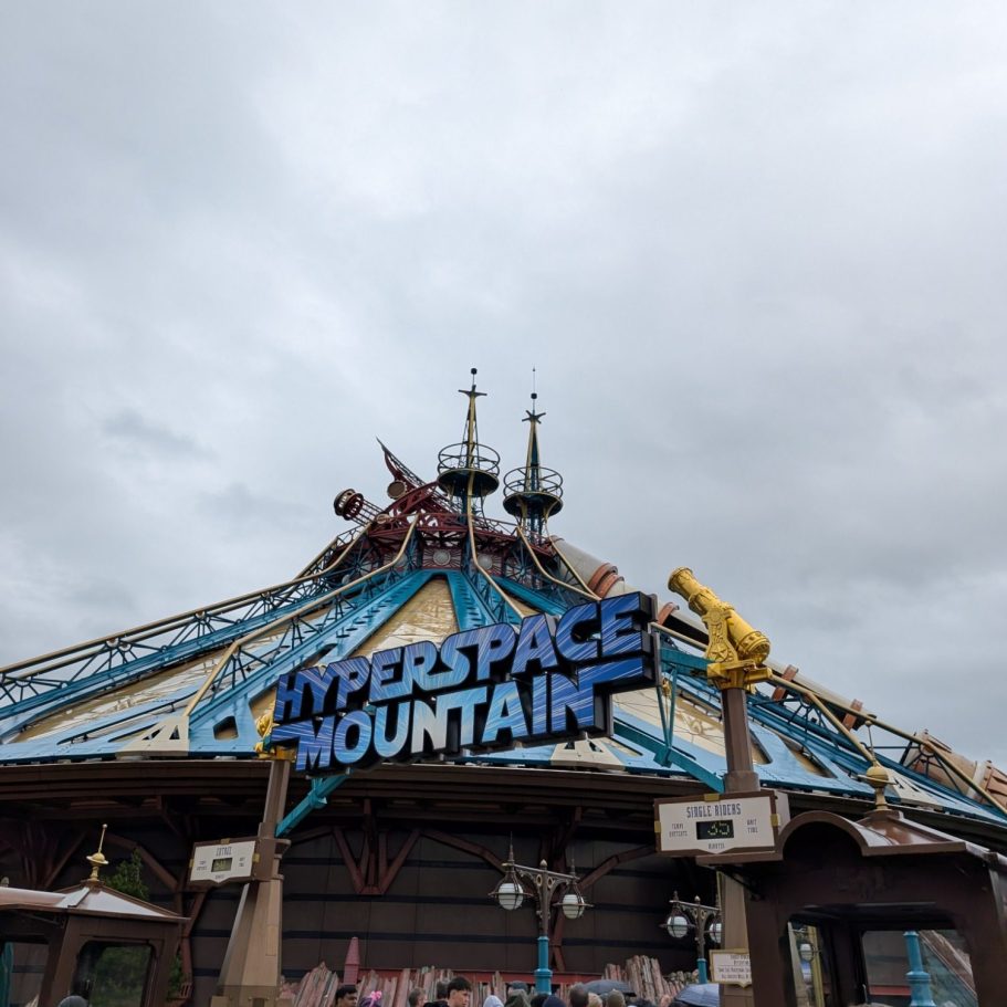 Sign for Hyperspace Mountain amusement ride under a cloudy sky.