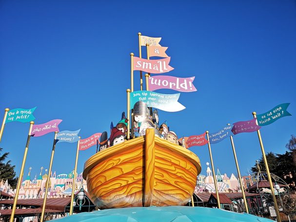 A yellow boat with flags, featuring a playful design against a clear blue sky.