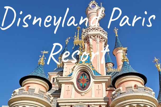 Pink castle with blue spires at Disneyland Paris, set against a clear sky.