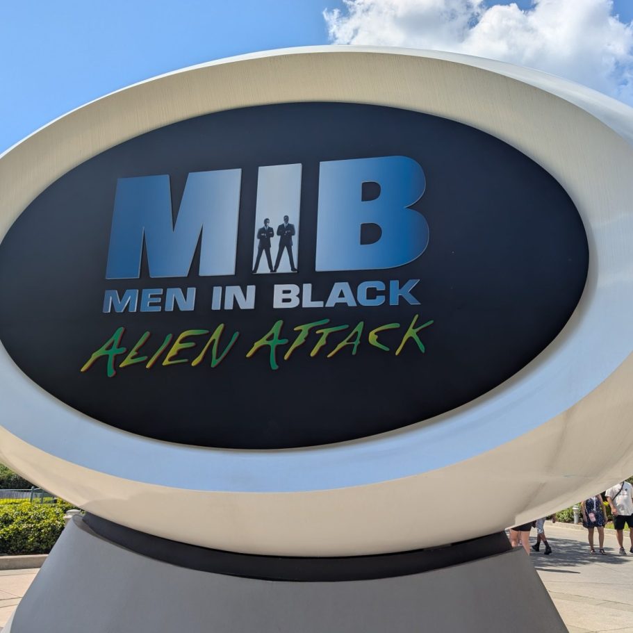 Sign for "MIB Men in Black: Alien Attack" attraction with a rounded design.