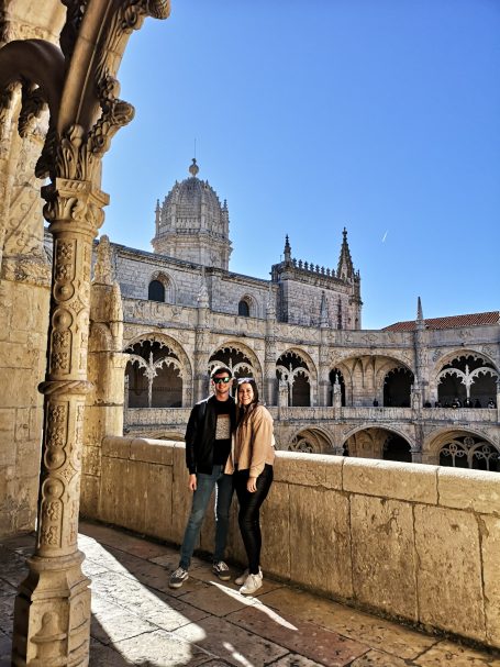 I&B's Founder & Husband posing under a stone archway against a blue sky at Jeronimos Monastery.