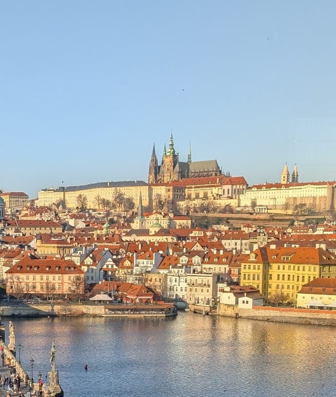View of Charles Bridge over the Vltava River with Prague's skyline in the background.
