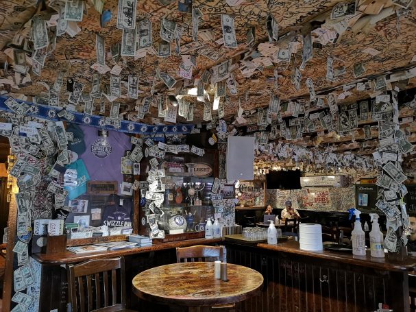 Interior of The Swizzle Inn bar decorated with money and memorabilia hanging from the ceiling.