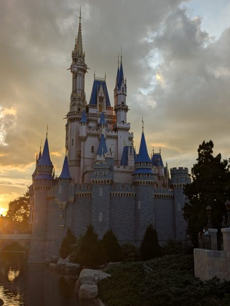 Cinderella's castle with spires, surrounded by trees at sunset at Magic Kingdom.