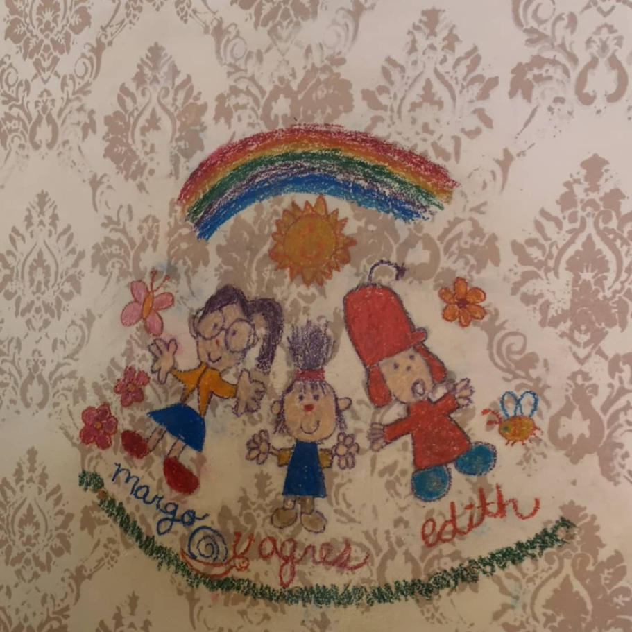 Children's drawings of two girls and a rainbow on a patterned wall.