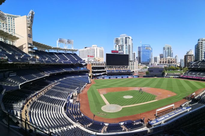 A panoramic view of Petco Park, baseball stadium in San Diego with blue skies and city buildings in the background.