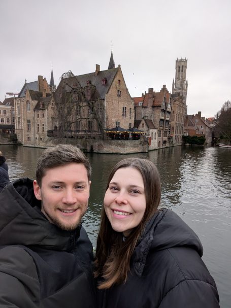 I&B's Founder & Husband posing in front of the Bruges Canal, with Rosary Quay in the background.