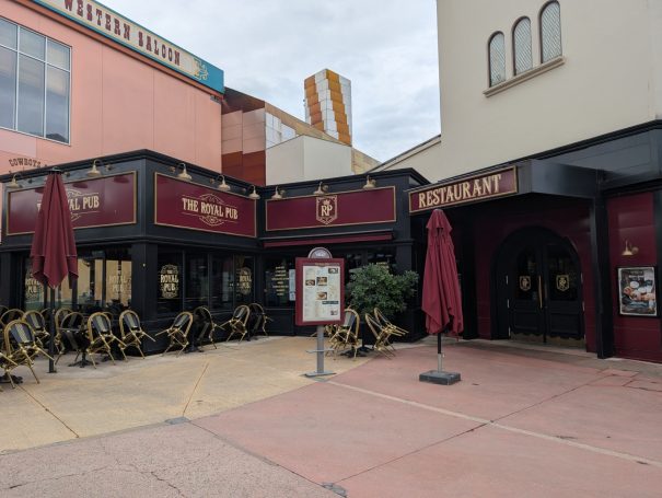 Exterior of a restaurant with outdoor seating and large maroon umbrellas.