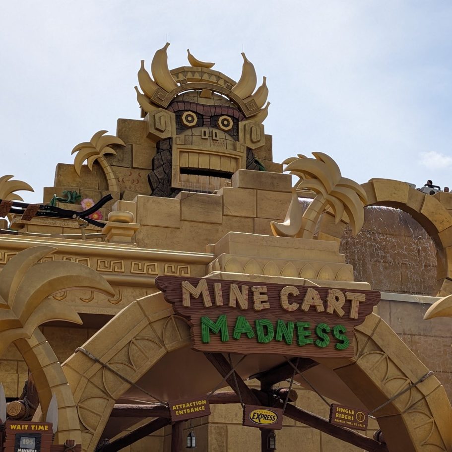 Entrance to an amusement ride featuring a large stone face and "Mine Cart Madness" sign.