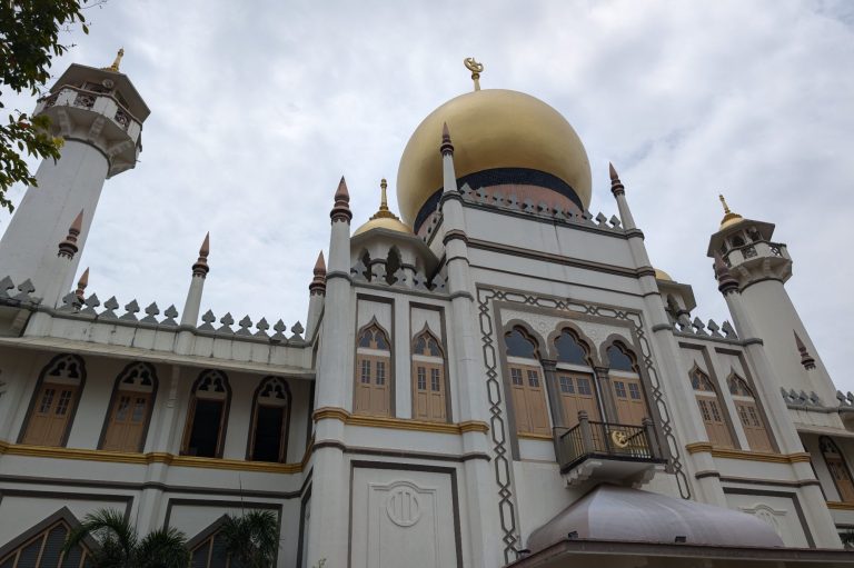 The grand building of Sultan Mosque in Singapore featuring a large golden dome and ornate architectural details.