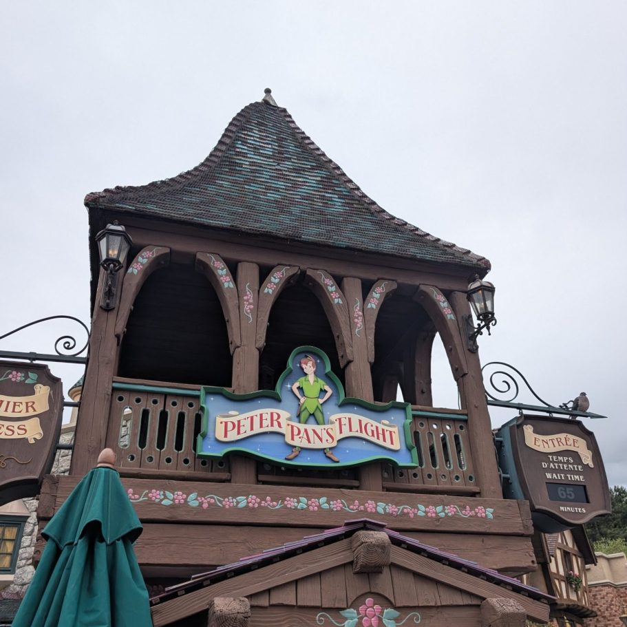 Brown tower with ornate details and a sign reading "Little Town Hall" under a cloudy sky.