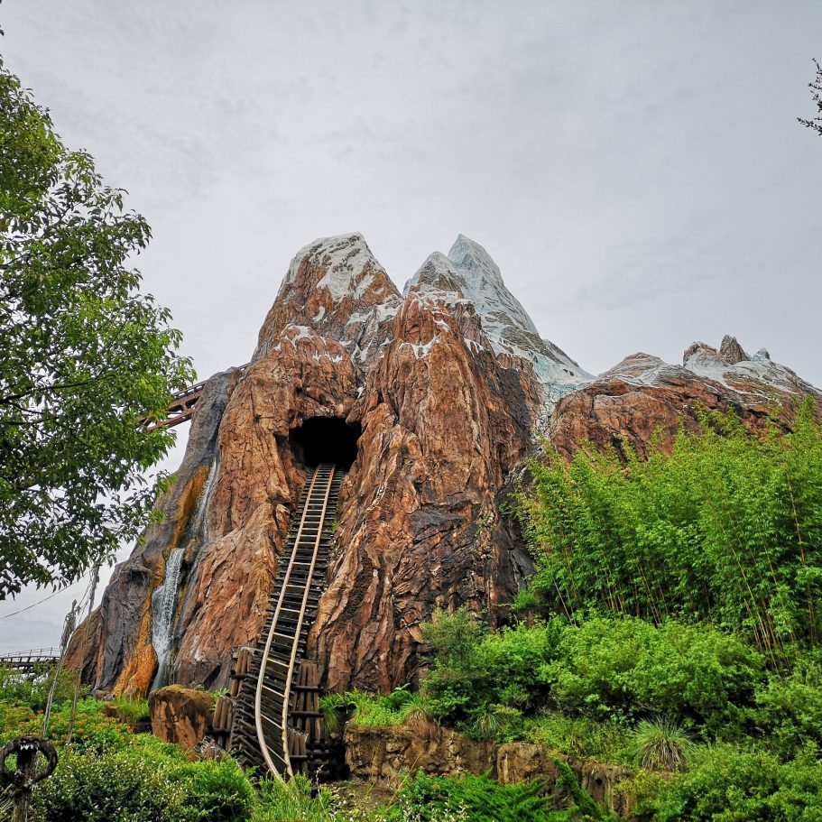 Mountain-themed roller coaster entrance with tracks leading inside a rocky cave.