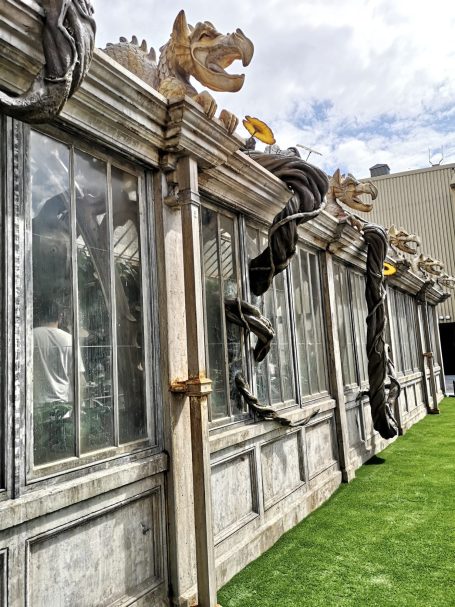 Decorative greenhouse with ornate animal sculptures along the roof and lush green grass. Located at Warner Bros Studio Tour.