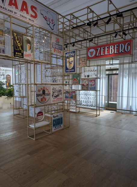 Art installation with posters displayed on a wooden framework in a spacious gallery.