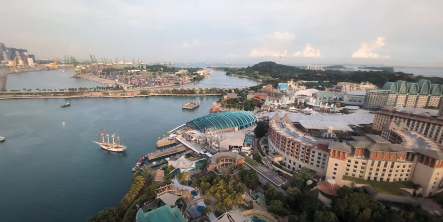 Panoramic view of a waterfront city with buildings, greenery, and boats in the water.