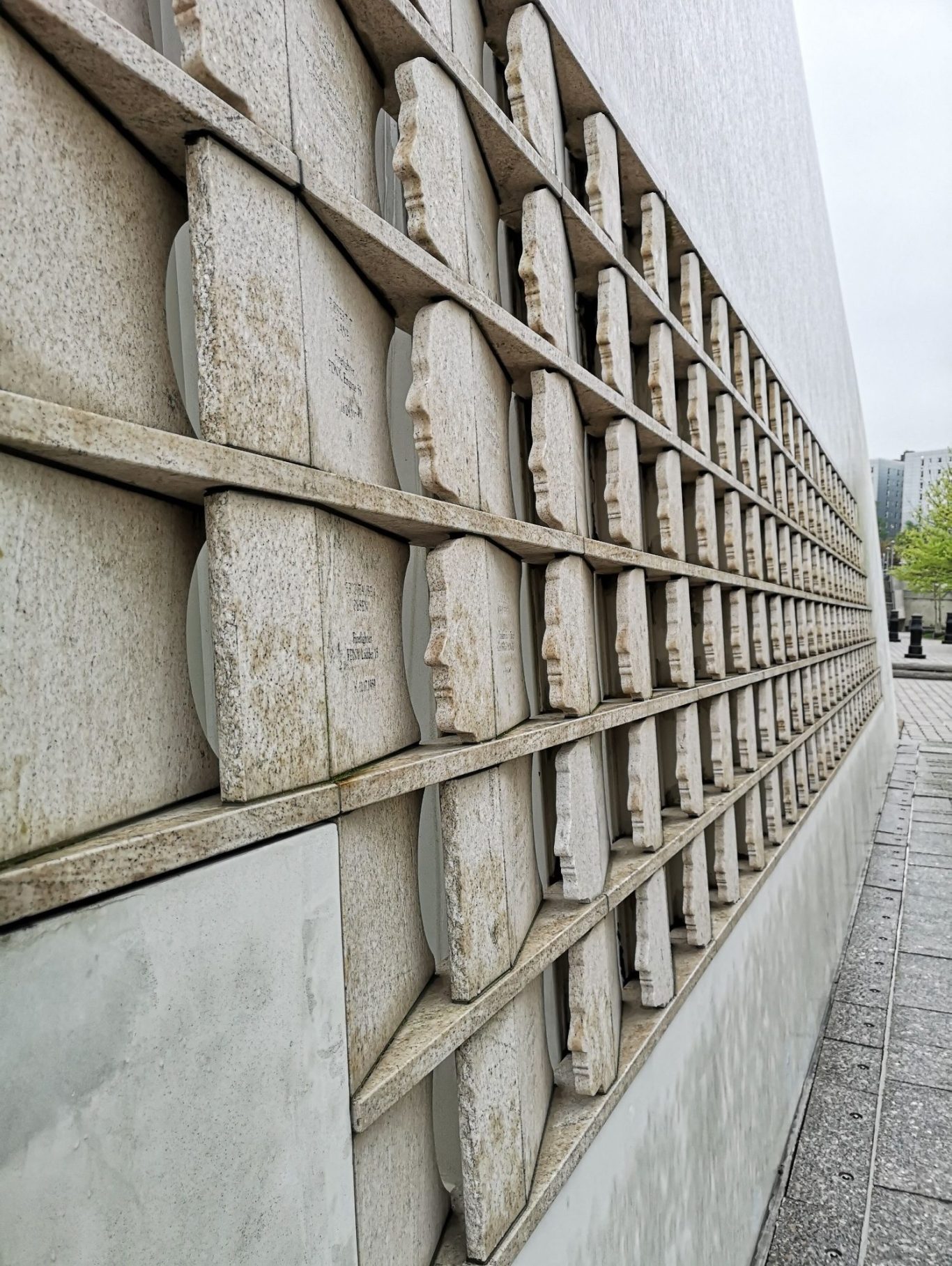 Textured wall featuring a pattern of circular stone panels and wooden slats. The 911 Memorial on Staten Island.
