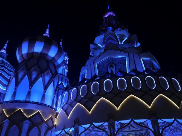 A brightly illuminated architectural structure with blue lights at night, located at Global Village in Dubai.