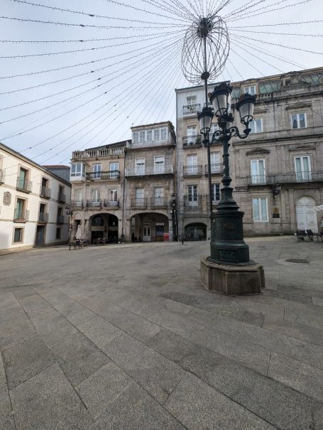 Plaza de la Constitución, an historic square with stone buildings and decorative street lamp under a canopy of lights.