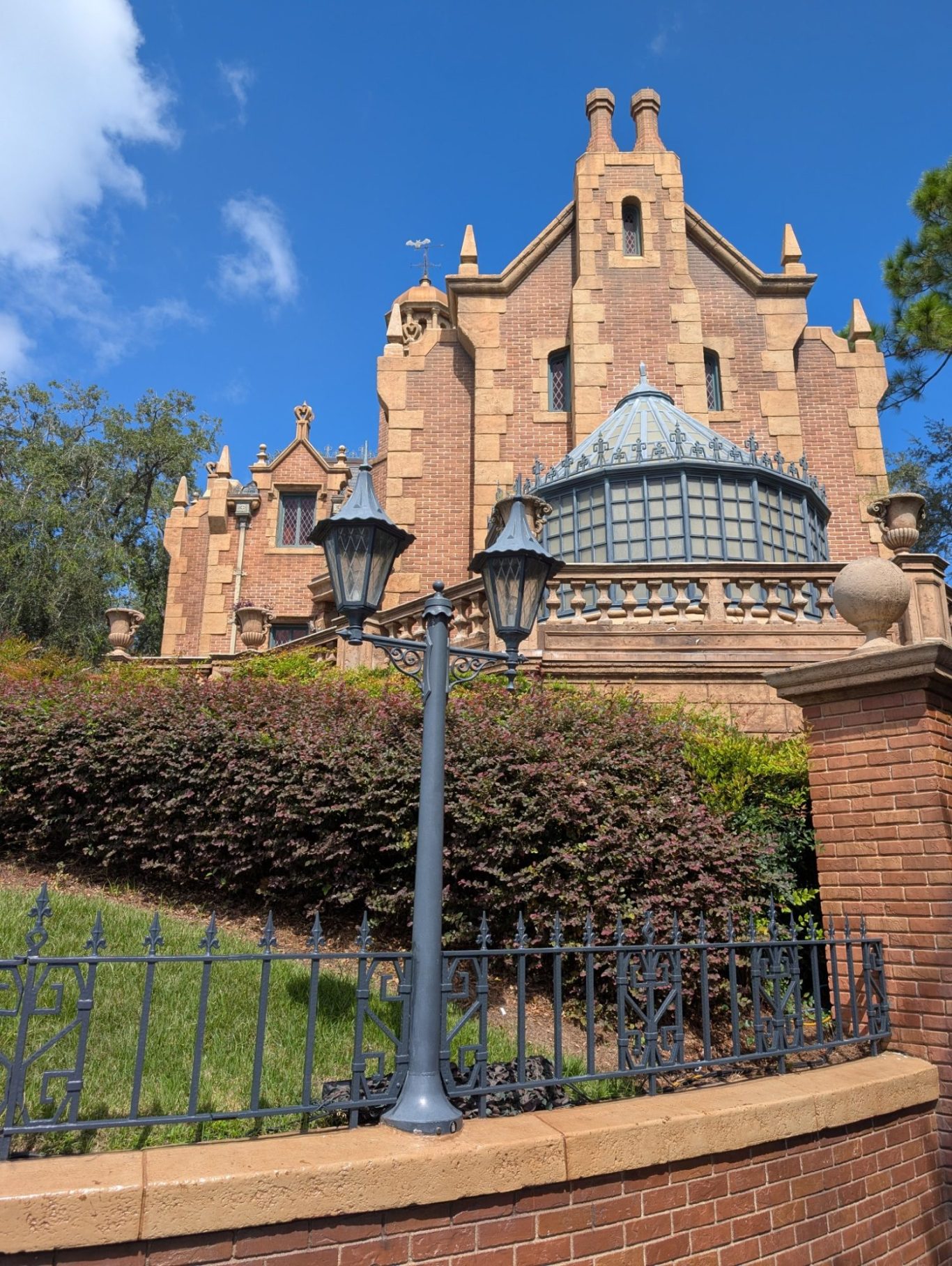 Victorian-style building with elaborate architecture and gardens under a blue sky.