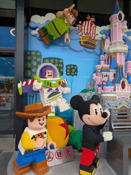 LEGO figures of Woody, Buzz Lightyear, Peter Pan, and Mickey Mouse in a vibrant display.
