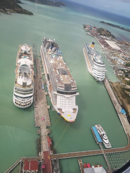 Bird's eye view of three large cruise ships docked in St John's Antigua, surrounded by turquoise waters.