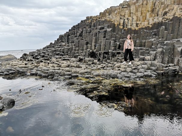 I&B's Founder standing on rocky shoreline with hexagonal basalt columns at the Giant's Causeway