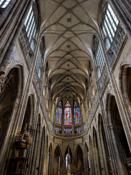 Gothic cathedral interior with high vaulted ceiling and stained glass windows.