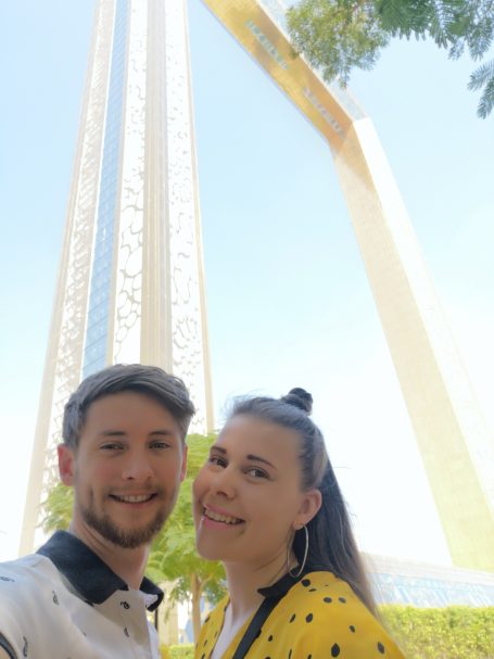 I&B's Founder & Husband posing ion front of a tall, golden frame structure known as the Dubai Frame