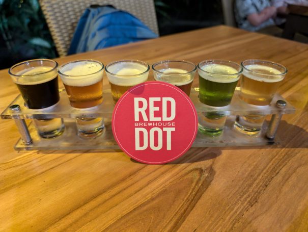 A selection of six shot glasses containing different coloured beers and a "Red Dot" coaster.