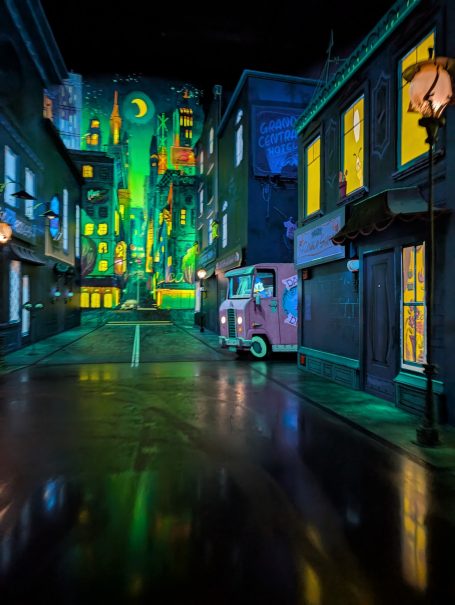 A vibrant, illuminated street scene with old buildings and a vintage van.
