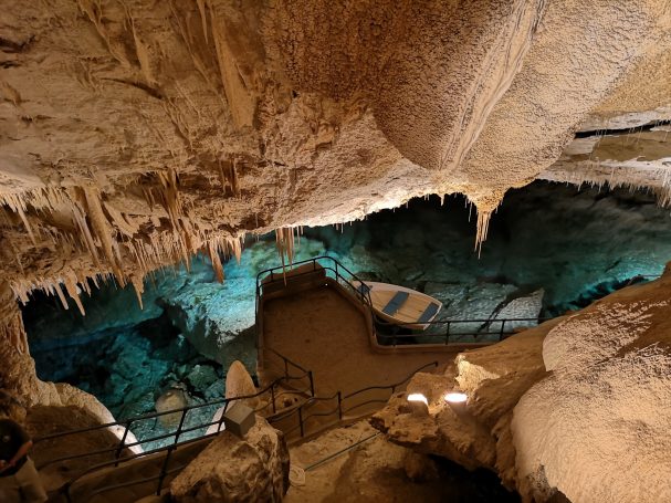 Crystal and Fantasy Caves, underground cave with stalactites, a pool of water, and a small wooden boat.