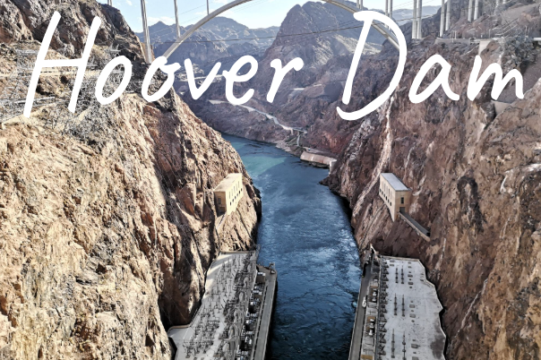 View of Hoover Dam with a river flowing through rocky terrain.