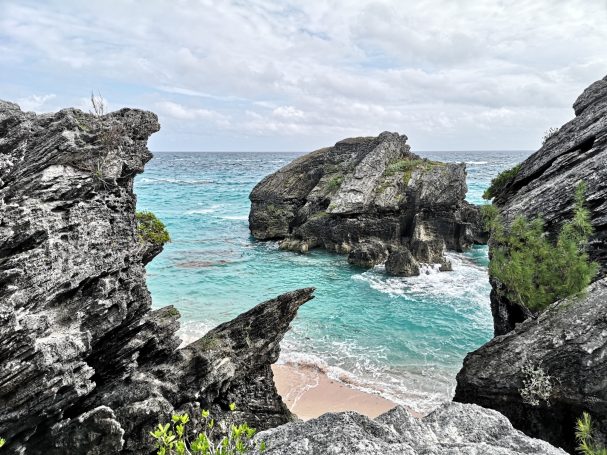 The rocky formations of Jobson's Cove with turquoise waves and sandy beach in a serene tropical setting.
