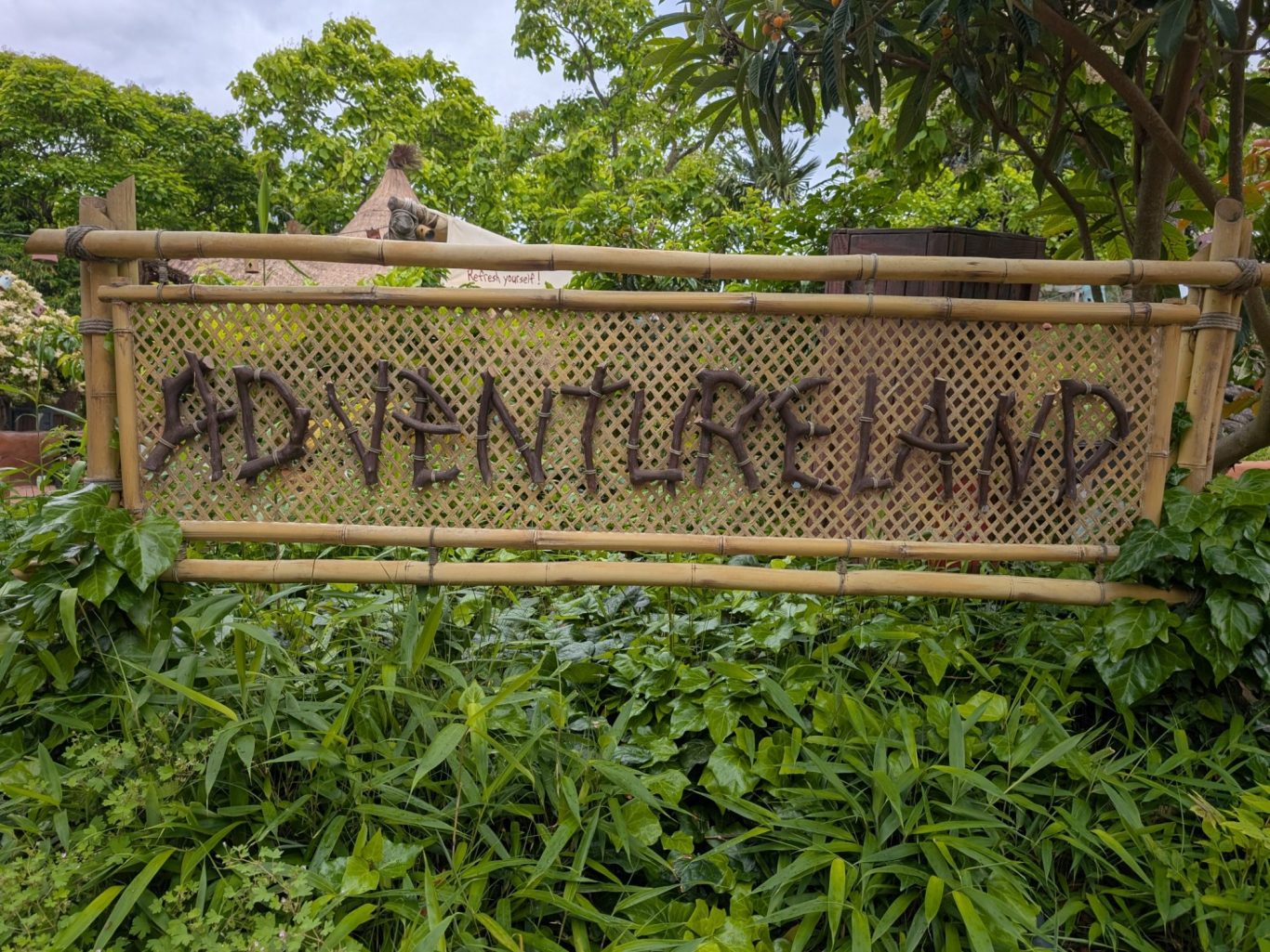 Sign reading "Adventureland" surrounded by green foliage.