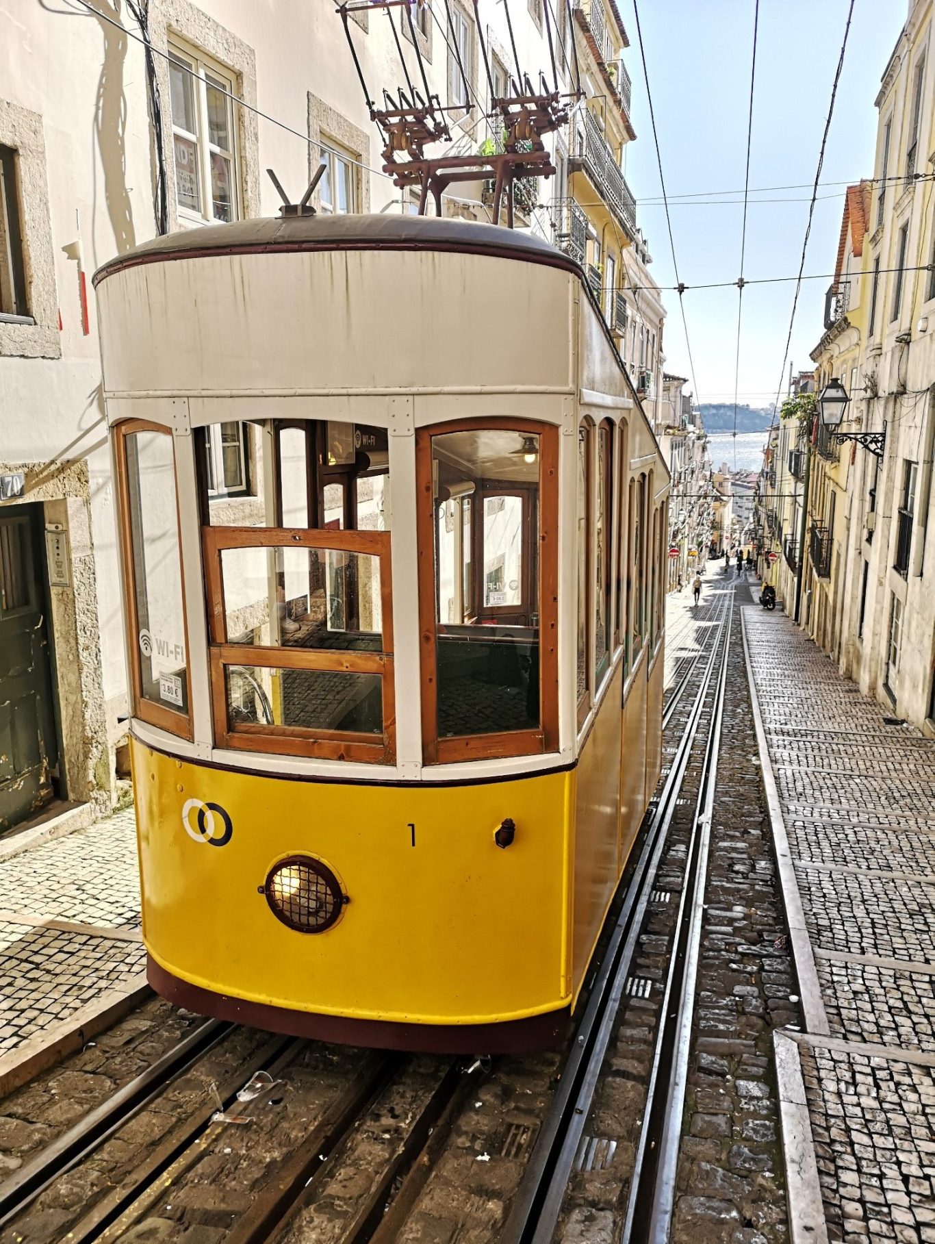 A view of Elevador da Bica. A vintage yellow tram on a steep street in Lisbon city.