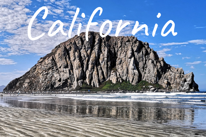Morro Rock coastal landscape of California with waves and bright blue sky.