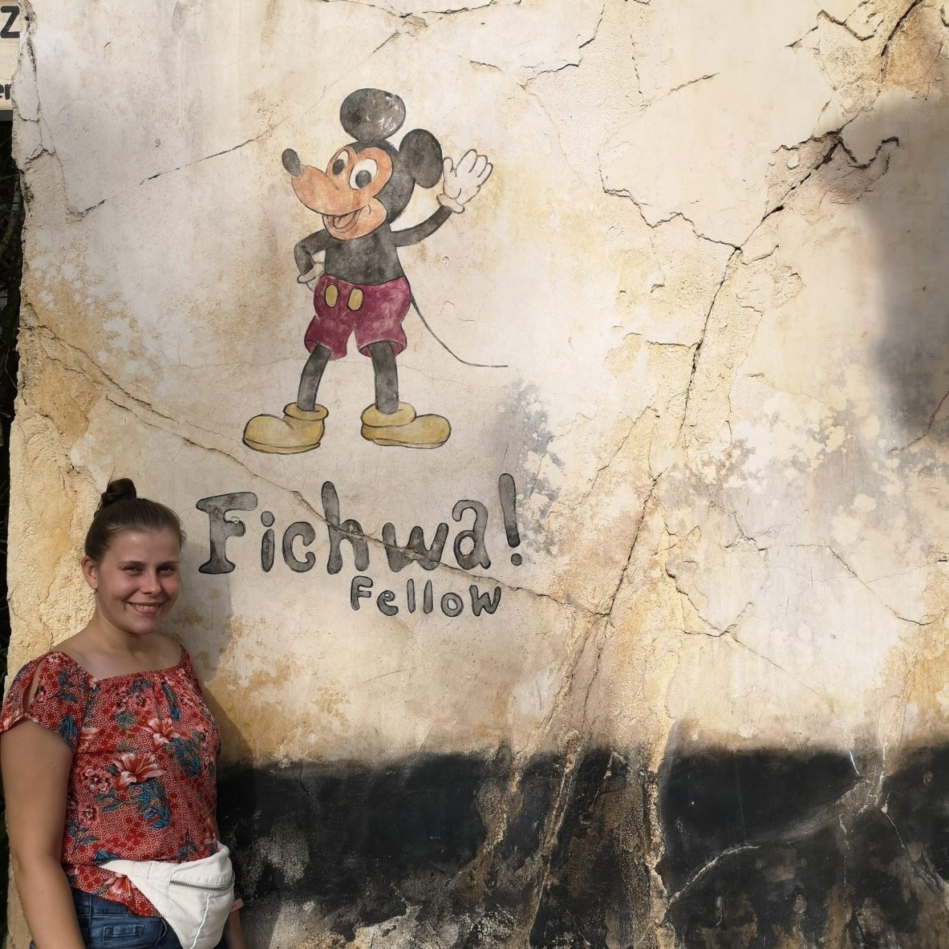 I&B's Founder stands beside a mural of Mickey Mouse with the text "Fichwa! Fellow" on a wall.