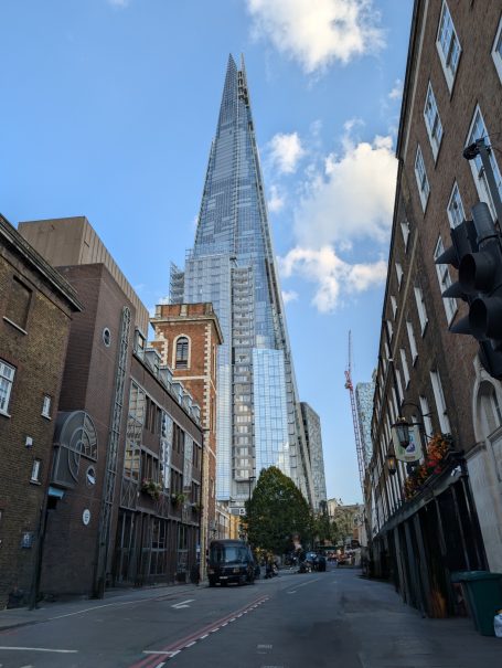 View of The Shard towering over a nearby street with buildings and traffic lights.