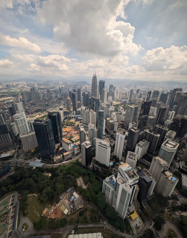 A panoramic view of a city skyline with tall buildings and scattered clouds.
