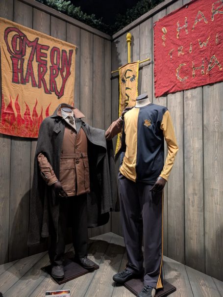 Display of two costumes from a fictional sports team, set against a rustic backdrop. Located at the Harry Potter Studio Tour, London.