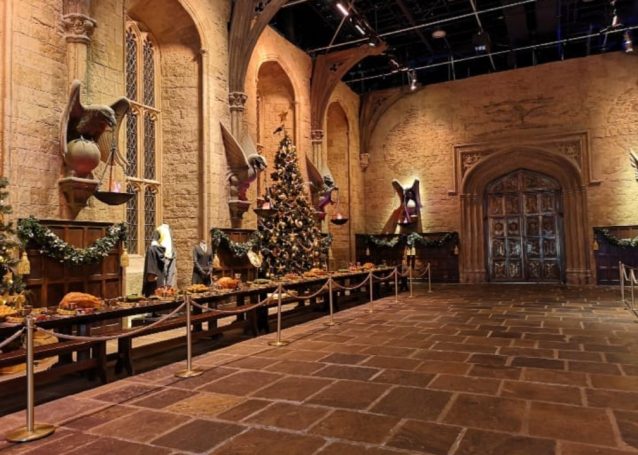 The Great Hall decorated with a Christmas tree and ornate stone walls. Located at the Harry Potter Studio Tour, London.
