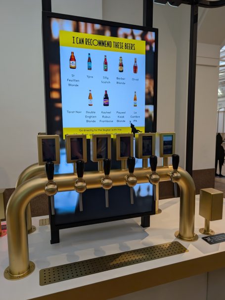A row of gold beer taps in front of a menu display of drink options.