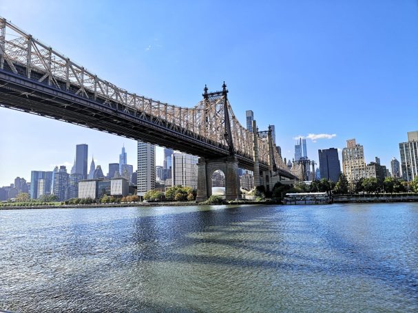 Queensboro Bridge spans over water with a skyline view of New York City in the background.